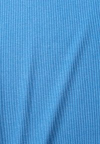 Textil som kännetecknas av en ljusblå färg, med smal vertikal ribbad struktur genom hela tyget, vilket skapar subtil djup och dimension.