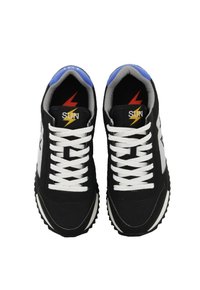 Scarpe sportive nere con lacci bianchi, dettagli grigi e tallone blu. Presentano un logo con un design a fulmine sulla linguetta.