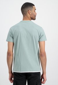 Tyrkysové tričko s krátkým rukávem a kulatým výstřihem. Měkká tkanina, volný střih a jednoduchý design s bílým akcentem na lemu.