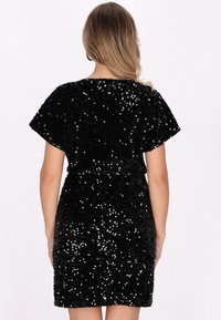 Rochie neagră din paiete cu mâneci scurte, caracterizată printr-o siluetă ajustată, textură lucioasă și o tăietură până la genunchi, potrivită pentru ținute de seară.