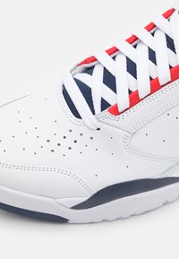 Sneaker din piele albă cu accente bleumarin și roșii. Prezintă perforații, șireturi în contrast și o talpă texturată. Design cu vârf rotund.