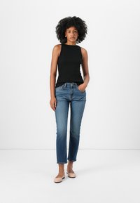 Zwart geribbelde tanktop, blauwe rechte jeans met een middelhoge taille en beige flats. Glad textuur; minimalistisch ontwerp.