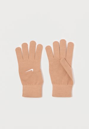 O pereche de mănuși tricotate bej cu manșete cu plasturi, una având un logo alb Nike swoosh pe partea din spate a mâinii.