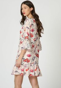 Vestido con estampado floral que presenta un fondo rosa claro, mangas cortas con volantes, un dobladillo escalonado y diseños de peces y corales coloridos.