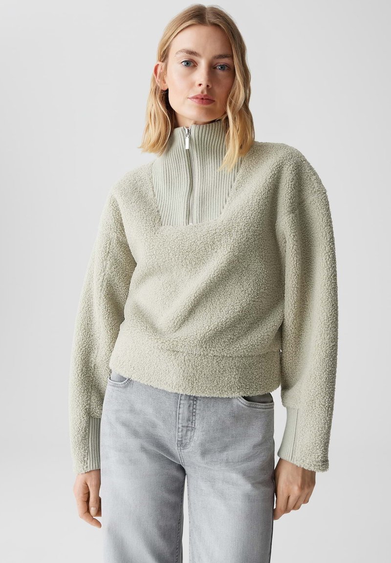 Pullover in pile verde chiaro con colletto alto a coste e dettaglio a zip a un quarto; tessuto strutturato e testurizzato; maniche ampie; vestibilità rilassata.