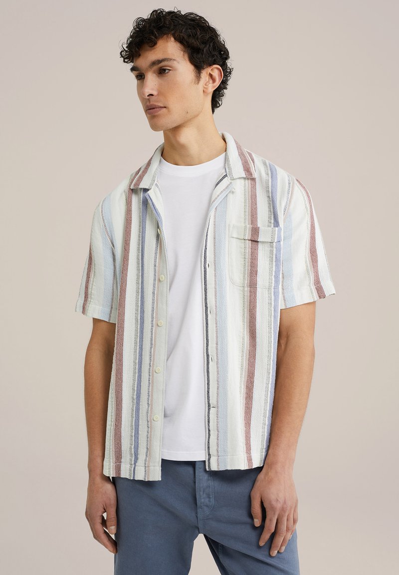 Camisa de manga corta con botones en tejido a rayas, que presenta tonos de blanco, azul y burdeos, con un bolsillo de parche en el pecho y corte holgado.