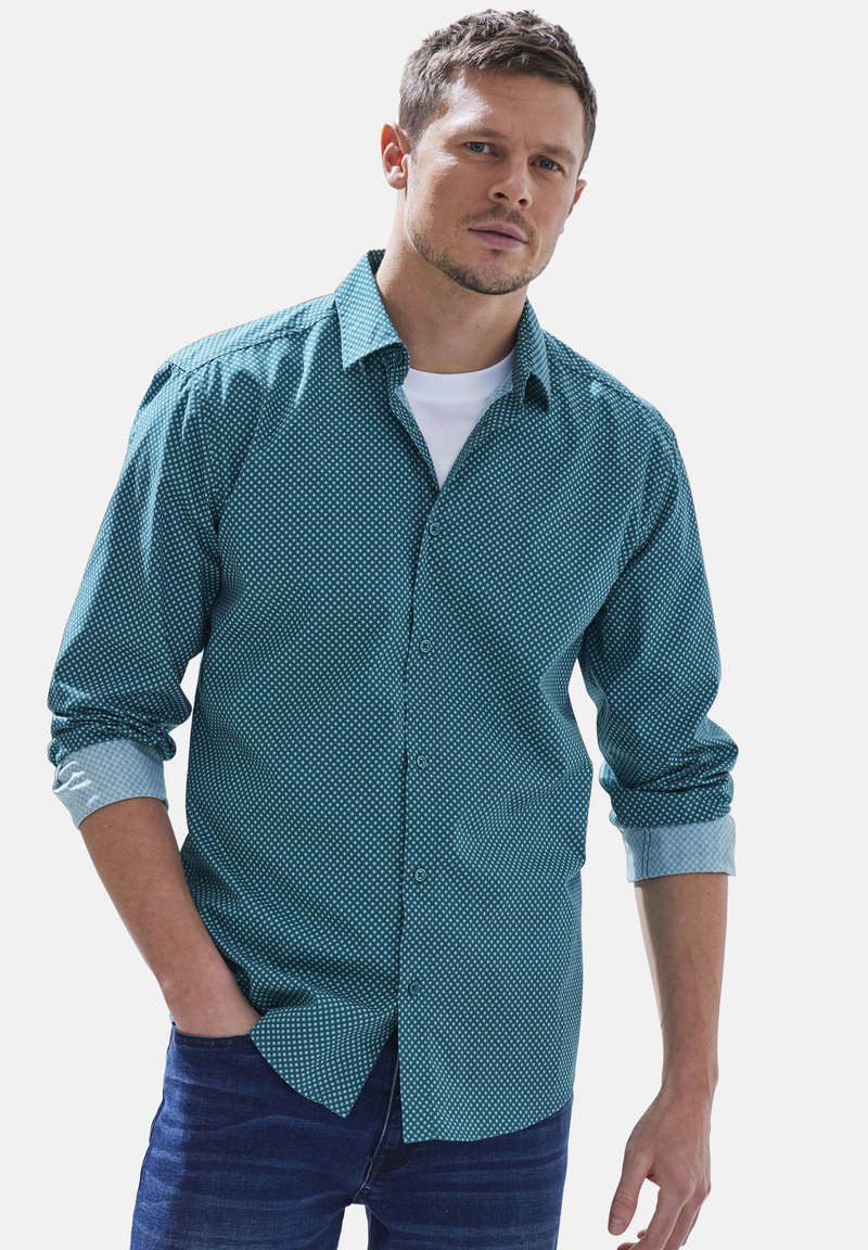 Türkisfarbenes Hemd mit Musterdesign und kontrastierenden hellblauen Manschetten, kombiniert mit dunkelblauen Jeans. Lässige Passform und aus Baumwolle.