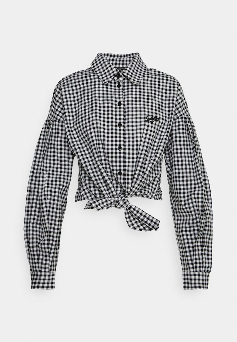 Chemise à carreaux vichy noir et blanc avec de longues manches bouffantes et un détail en nœud à l'avant, comportant des boutons noirs et une broderie de logo.