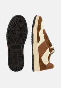 Hnědé a krémové tenisky z semišového a koženého materiálu, s černou gumovou podešví a šněrováním.