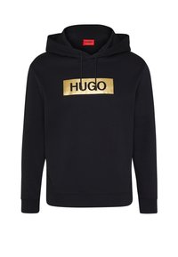 Felpa nera con cappuccio e logo rettangolare dorato che riporta la scritta "HUGO" centrata sul petto, dotata di cappuccio con lacci e maniche lunghe.