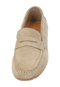 Beige Wildleder-Mokassin mit flacher Sohle, gestickten Details und einem Akzentband. Glatte Textur und abgerundete Zehenform.