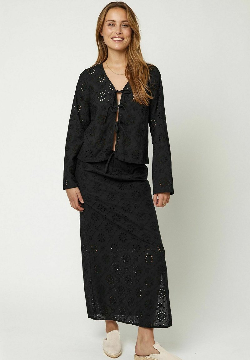 Zwart geborduurd twee-delig outfit met een knoopsluiting aan de voorkant, lange mouwen blouse en een bijpassende enkel-lange rok met bloemen uitsparingen.
