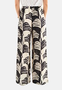 Pantalones de pierna ancha en negro y crema con un patrón de hojas, con cintura elástica y un tejido ligero y texturizado.