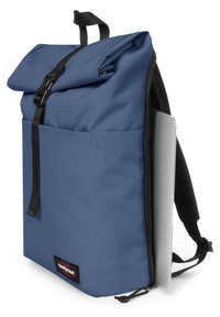 Zaino blu a chiusura roll-top realizzato in tessuto resistente, con una tasca frontale, spallacci neri e un compartimento per laptop visibile su un lato.