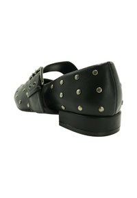 Zapato plano de cuero negro con tachuelas redondas plateadas, hebilla cuadrada y una correa en la parte superior.