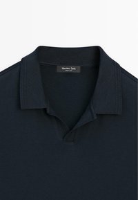 Polo noir à manches courtes avec col côtelé et une étiquette « Massimo Dutti » à l'intérieur du col.