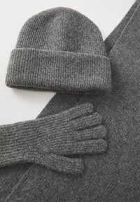 Hall grey kootud beanie, kindad ja sall, mis on valmistatud tekstureeritud kangast. Beanie'l on krae; kindadel on soonilised sõrmed. Kõik esemed on kooskõlastatud tooni.