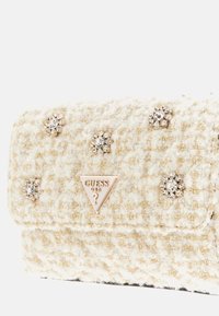 White textured handbag with gold threading, embellished with silver flower-shaped rhinestones and a gold triangle logo.