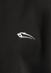 Czarna bawełniana tkanina z białym haftowanym logo o eleganckim, zaokrąglonym kształcie. Tekstura jest gładka i miękka.