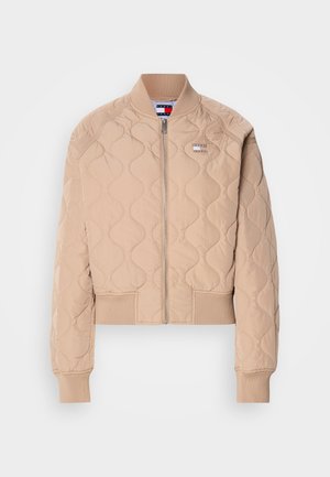Prešívaná bomber bunda v svetlo béžovej farbe s predným zipsom, rebrovanými manžetami a lemom, a s logom na ľavej hrudi.