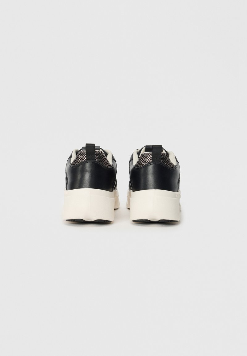 Czarne skórzane sneakersy z siateczkowymi wstawkami i kremowymi gumowymi podeszwami, z pętelką z tyłu dla łatwego zakładania.