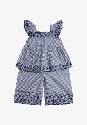 To-delt outfit med marineblåt og hvidt ternet mønster, med flæse stropper og broderede blomsterkanter på toppen og vidde shorts.