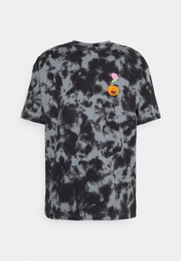 Camisa de manga corta en tie-dye negro y gris con pequeño bordado de un balón de baloncesto naranja de Nike y un detalle de flor rosa en el pecho.