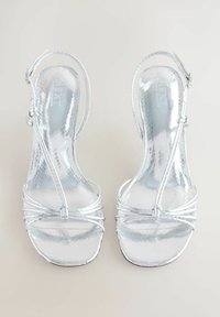 Ezüst metál színű pántos szandál letisztult kialakítással, texturált felülettel, nyitott orral és állítható boka pántokkal.