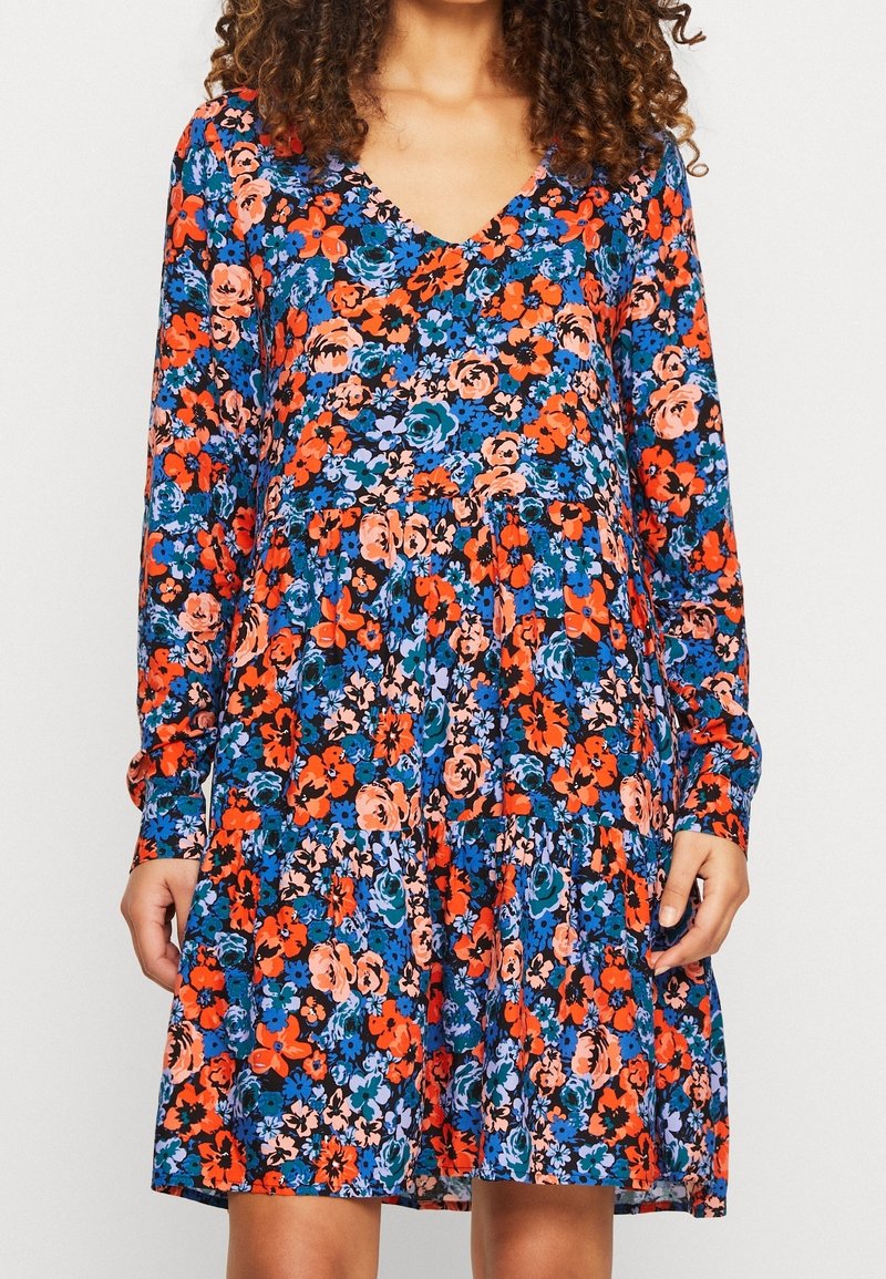 Květinové šaty s dlouhým rukávem a V výstřihem, s černým pozadím a živými vzory květin v oranžové, modré a růžové barvě. Detaily ve tvaru zvonku.