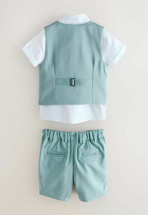 Chemise blanche à manches courtes avec gilet bleu clair gracile muni d'une boucle à l'arrière et short à taille élastique assorti avec poches, étalés à plat sur un fond neutre.