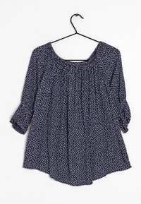 Granatowa bluzka o luźnym kroju i okrągłym dekolcie, zdobiona białymi kropkami, z rękawami o długości trzech ćwierci oraz marszczeniem przy dekolcie.