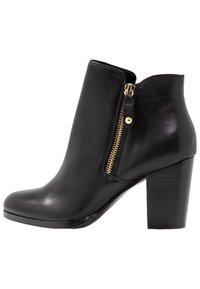Bota de piel negra hasta el tobillo con una cremallera dorada lateral, punta redonda y un tacón cuadrado texturizado. Acabado suave con detalles de costura mínimos.