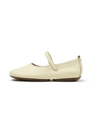 Cremefarbener Mary Jane flacher Schuh mit abgerundetem Zehenbereich, verstellbarem Riemen und flacher brauner Sohle, seitlich auf weißem Hintergrund dargestellt.