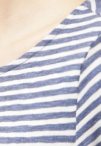 Top in tessuto rigato con strisce orizzontali blu e bianche, caratterizzato da una profonda scollatura a V e da una consistenza morbida.