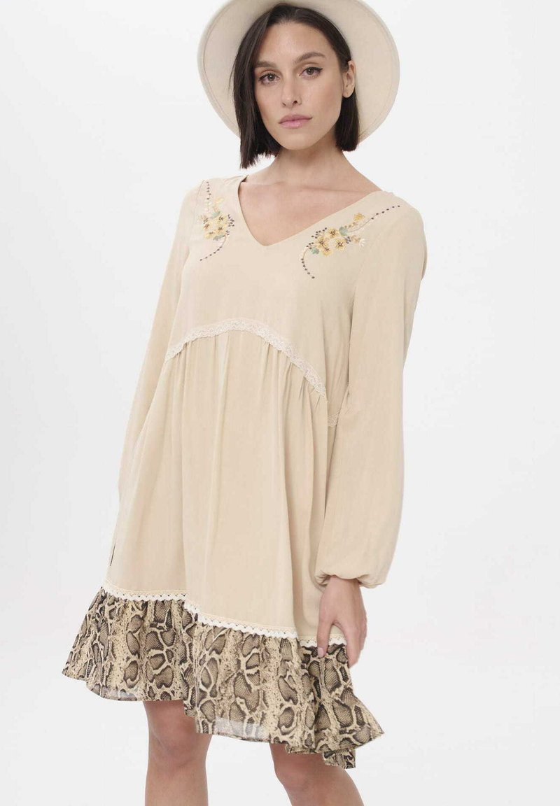 Beige lange mouw jurk met een V-hals, bloemenborduurwerk, kanten rand en een gerimpelde slangenprint onderzoom. Lichtgewicht stof.