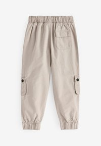 Beige Cargo-Hosen mit elastischem Bund, schmal zulaufenden Säumen, seitlichen Taschen mit Klappen und einer Gesäßtasche. Weicher, strapazierfähiger Stoff.