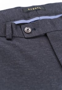 Dunkelgraue maßgeschneiderte Hosen aus strukturiertem Stoff. Verfügt über einen Knopfverschluss, Gürtelschlaufen und ein dezentes Muster. Markenetikett innen sichtbar.