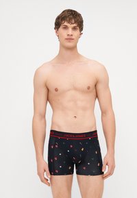 Fekete boxer nadrág ünnepi mintázattal, beleértve a díszeket és a cukornádat, piros elasztikus derékkal, amelyen a "JACK & JONES" felirat szerepel.