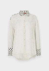 Bluza albă cu nasturi, cu mâneci lungi, mici buline negre pe tot corpul și buline negre mai mari pe guler și manșete.