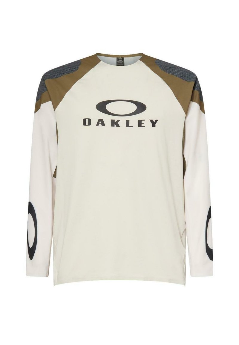 Camiseta beige de manga larga de Oakley con paneles en los hombros marrón y gris oscuro, logo en el pecho y logos circulares en las mangas.