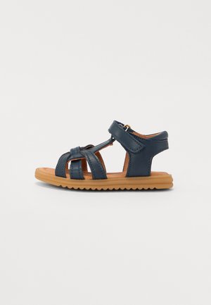 Navy blue leather sandal with a strappy design, adjustable Velcro closure, and a brown rubber sole featuring a textured pattern.