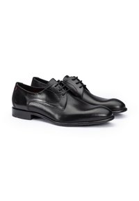 Schwarze Leder-Halbschuhe mit glattem und perforiertem Design. Sie verfügen über eine abgerundete Zehenpartie, eine Schnürung und einen niedrigen Absatz. Dezente rote Akzente.