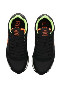 Ein Paar schwarze Sneakers mit leuchtend grünen Innenräumen, orangefarbenen Akzenten und dem Text "LAUFE SCHNELLER ALS DU KANNST" auf den Zungen, von oben betrachtet.
