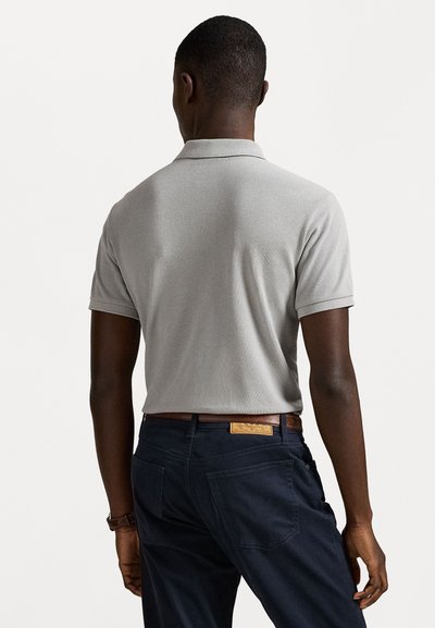 Γκρι πόλο πουκάμισο με υφή, κοντά μανίκια και γιακά; φορεμένο με σκούρα ναυτικά παντελόνια και καφέ δερμάτινη ζώνη.