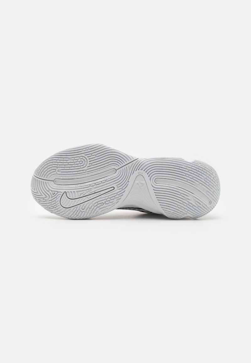Suela de zapatilla blanca con un patrón de tracción detallado, swoosh de Nike en relieve y nombres grabados sobre un fondo blanco liso.