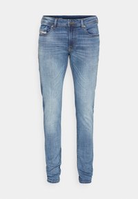 Blå denimjeans med slim fit, med subtila blekningsdetaljer, fem fickor och gylf med dragkedja. Materialet visar typisk denimstruktur och färgvariationer.