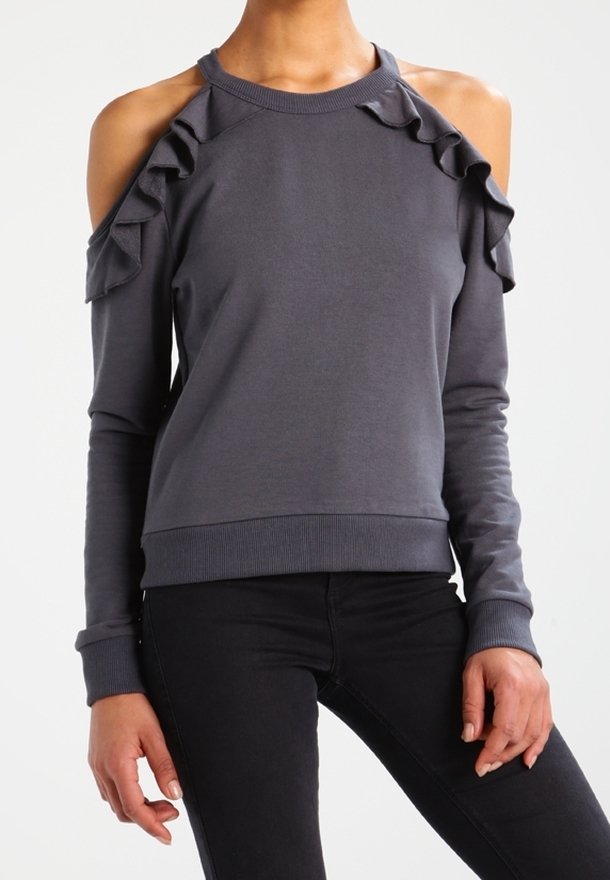 Sudadera gris con diseño de hombros al aire y acentos con volantes. Mangas largas y puños acanalados. Tela suave, forma ajustada y estilo relajado.
