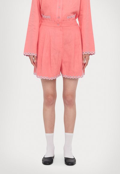 Shorts en lin rose corail avec broderie blanche en forme de coquille le long des ourlets et des poches. Comprend des passants de ceinture et un design plissé.