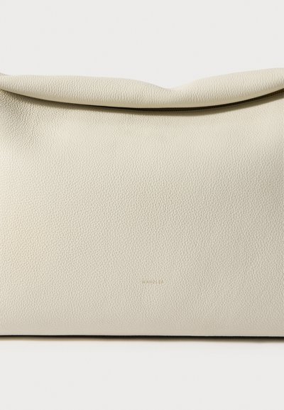 Puha bézs bőr kézitáska lehajtós tetővel és finom arany dombornyomott márkanévvel az elején, középen.