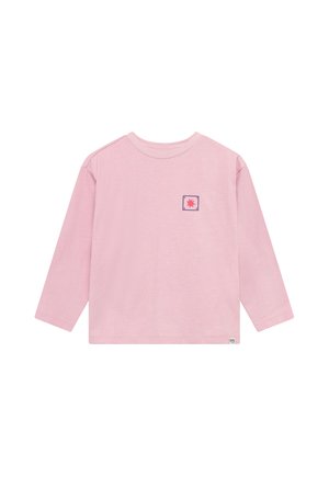 Chemise rose clair à manches longues avec un petit emblème étoile rouge dans un carré violet sur la poitrine gauche et une petite étiquette blanche près de l’ourlet inférieur.